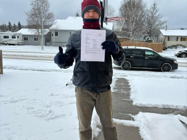 Khách hàng cầm thư đề cử định cư Alberta – ảnh chụp tại Canada, ngoài trời tuyết – New Life Immigration