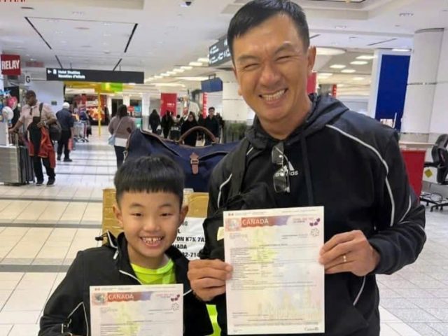 Cha và con trai cầm visa Canada tại sân bay, đánh dấu khoảnh khắc đoàn tụ sau khi định cư thành công cùng New Life Immigration 2